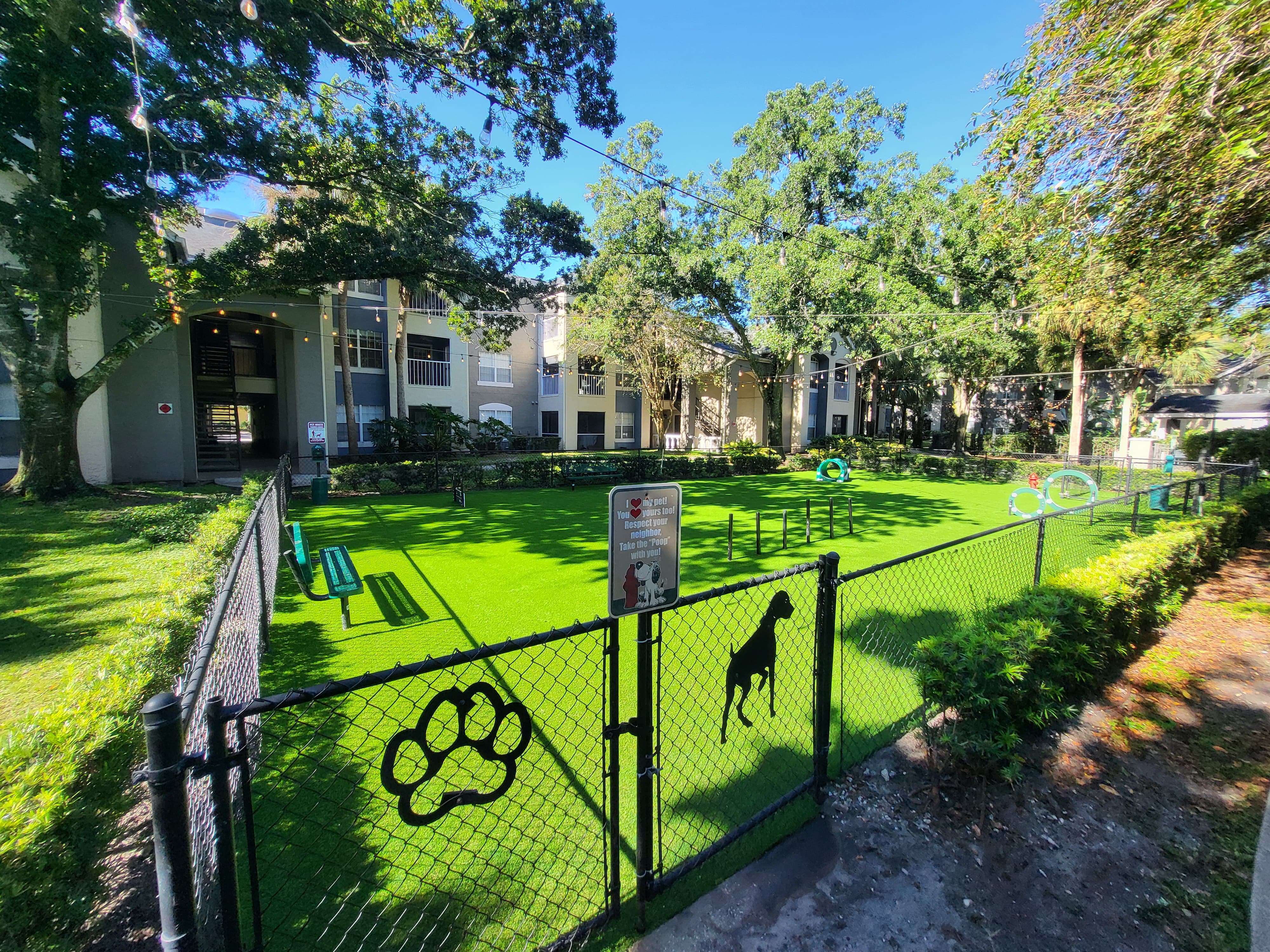 Tree-lined community dog park with pet turf